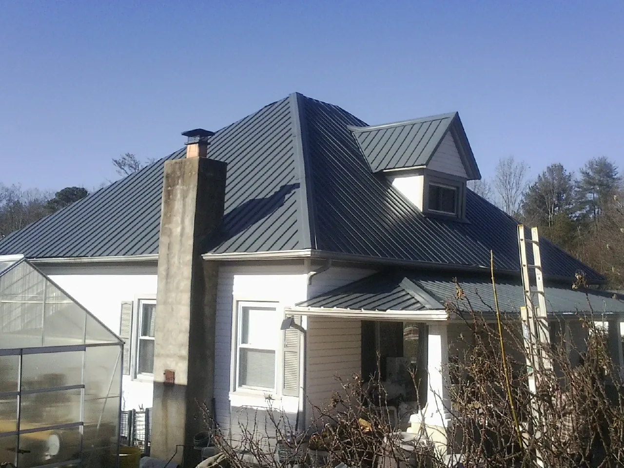 Dark blue standing seam metal roof on a white farmhouse with dormer — Slate & Tile Roof Repair by Roofing Brothers in Summit