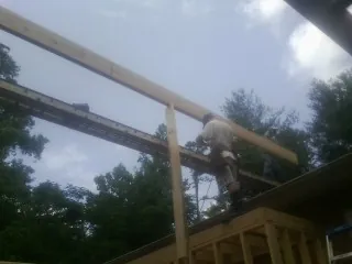 Carpenter setting a ridge beam over a new addition frame — Ice Dam Removal by Roofing Brothers in Summit