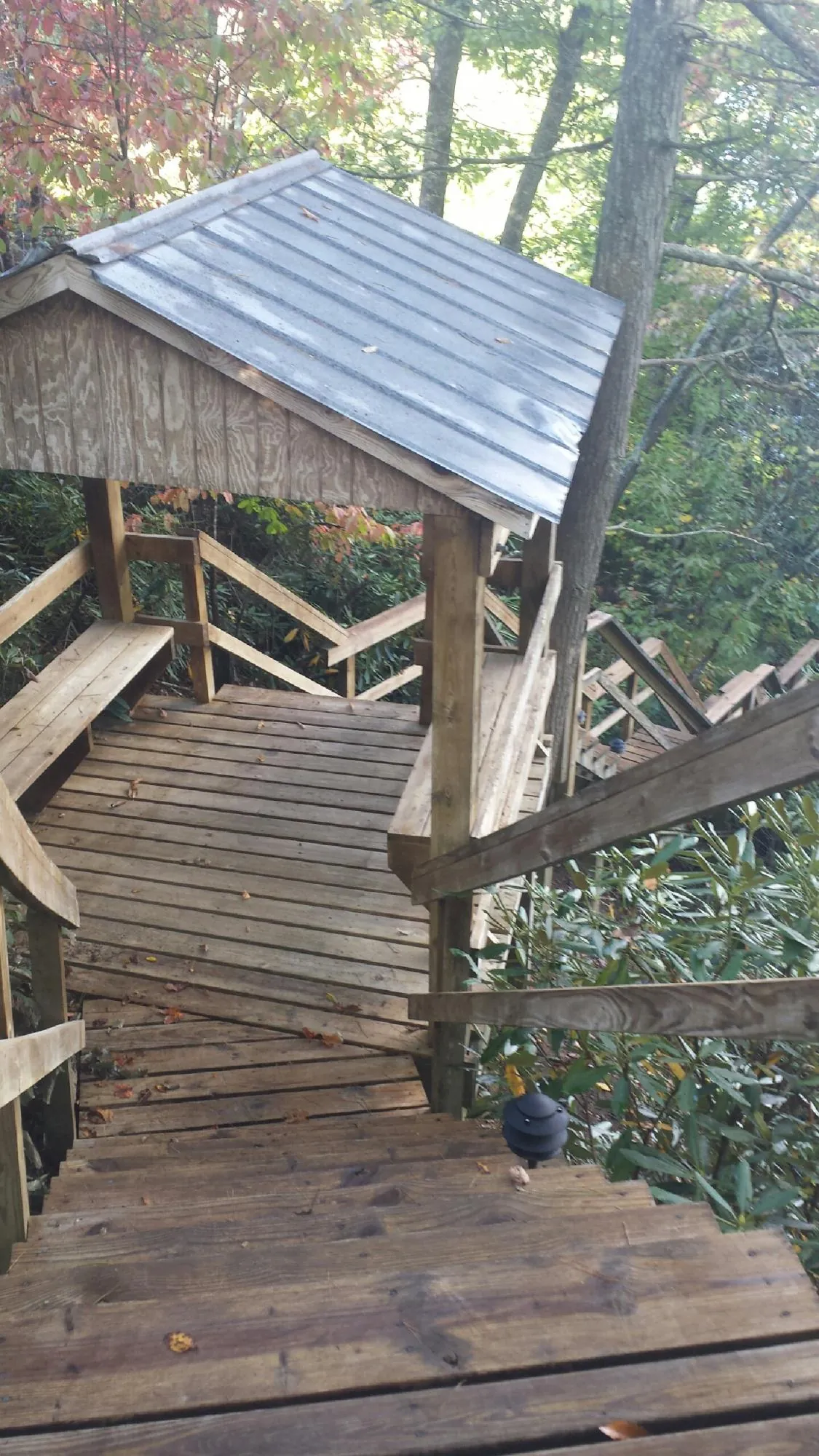 Metal roofed shelter over wooden steps on a wooded walkway — Skylight Repair & Installation work by our crew in Summit